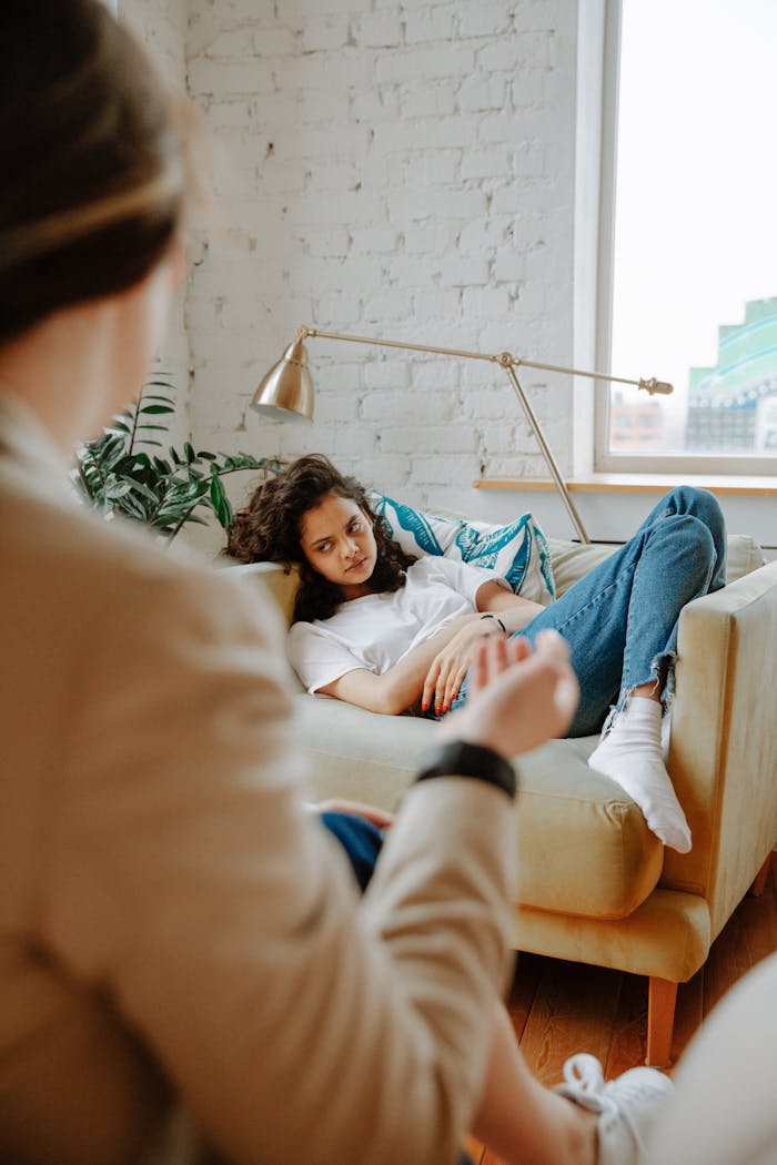 brand-01 A therapist converses with a young adult on a sofa, focusing on mental health.